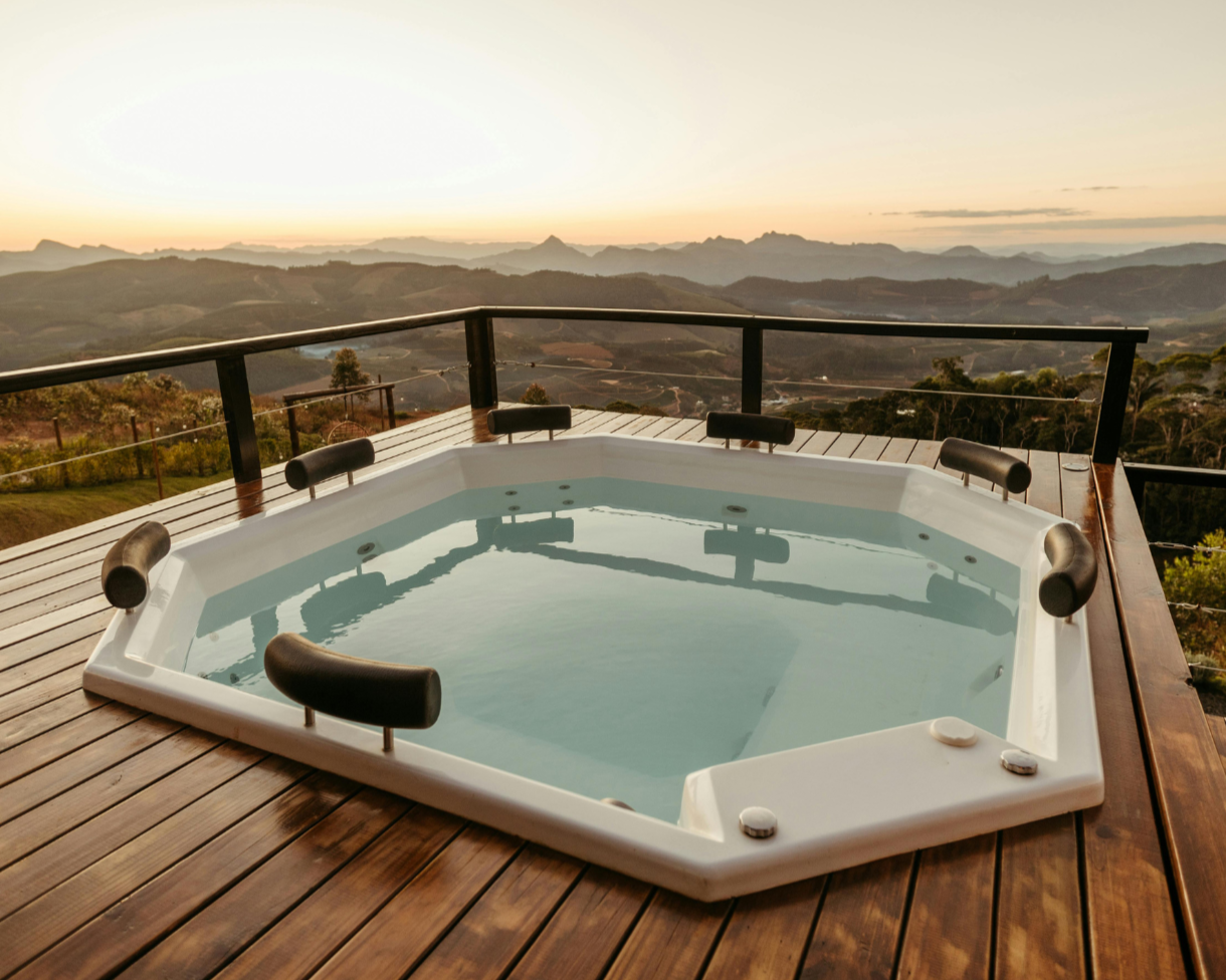 Hot tub jacuzzi on a wooden deck with mountain views during sunset