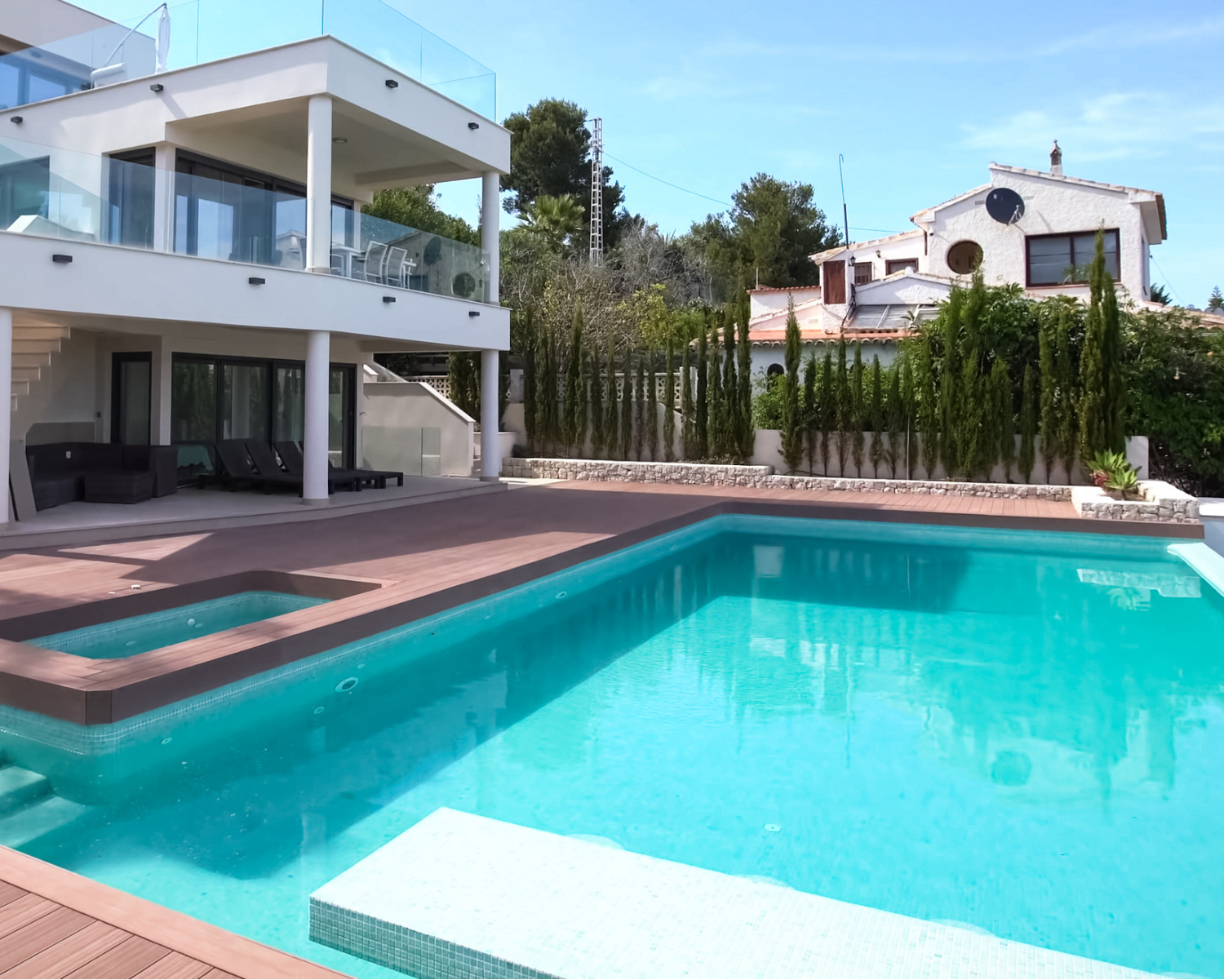 Modern house with a pool and surrounding garden on a sunny day