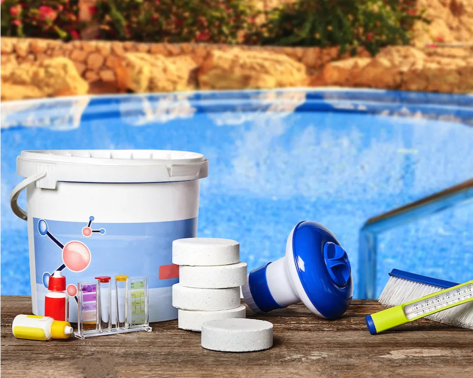 Pool cleaning tools and supplies on a wooden deck by a pool.