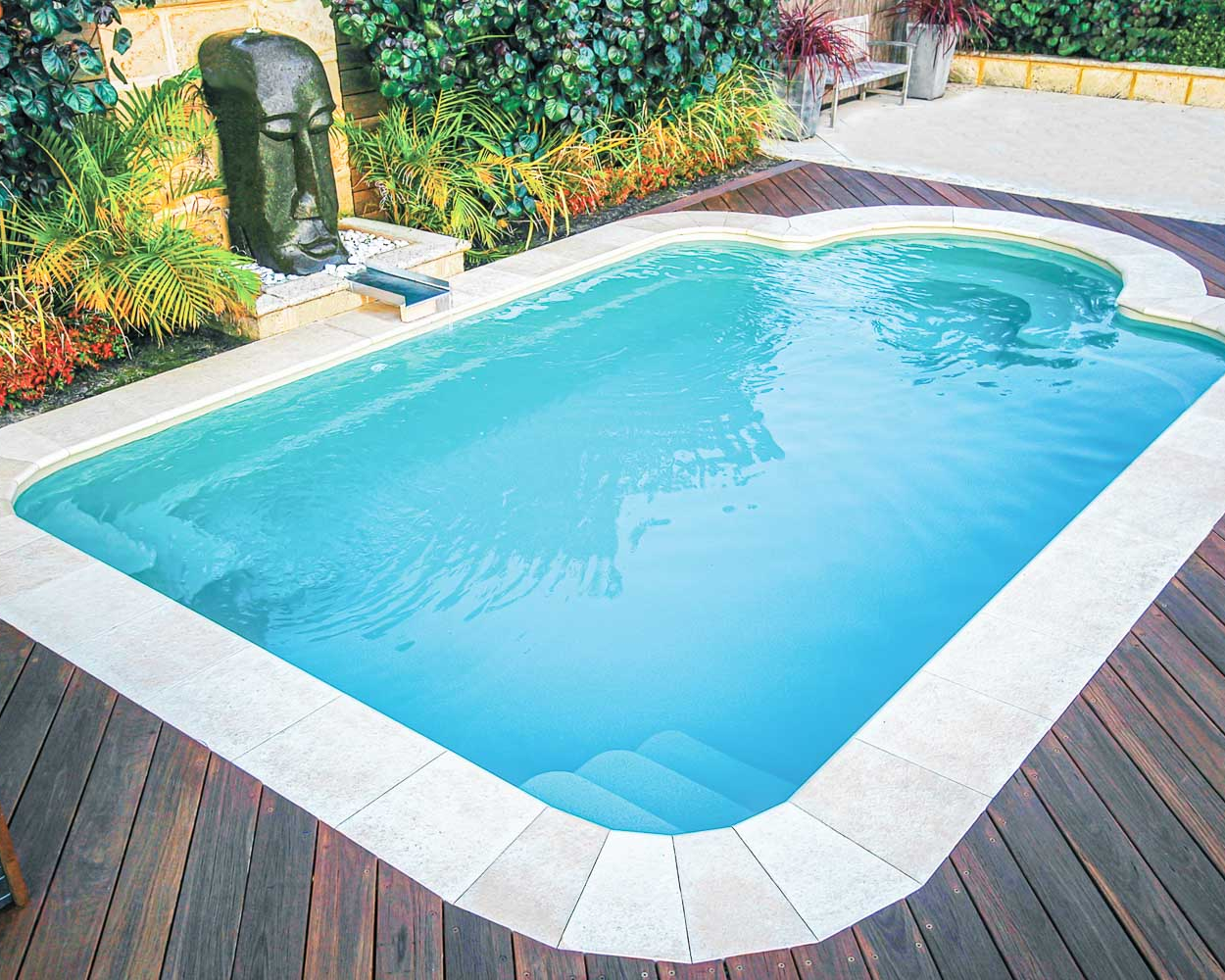 Rectangular FRP pool with white coping on a wooden deck area.