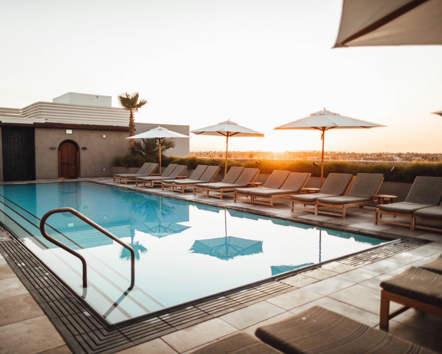 Pool area with lounge chairs and umbrellas at sunset