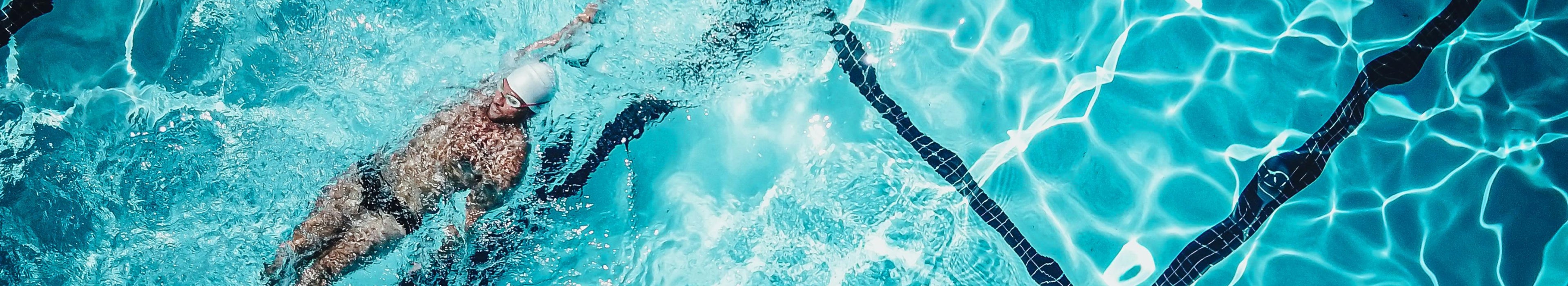 Person swimming in a pool with clear blue water and black lane dividers.
